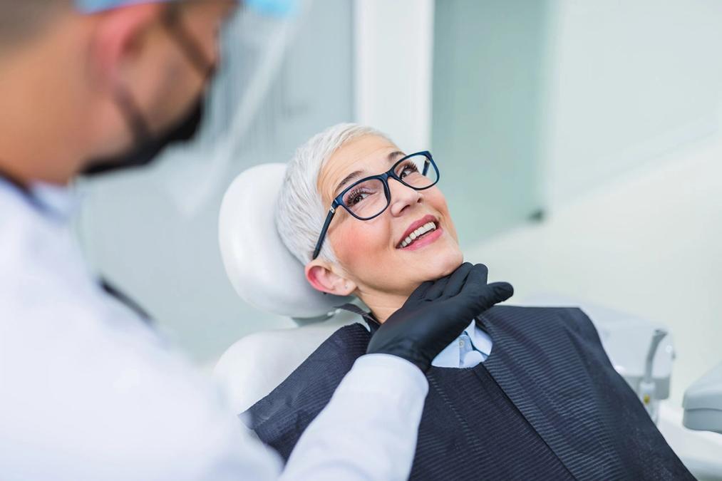a woman is sitting in a dental chair talking to a dentist .