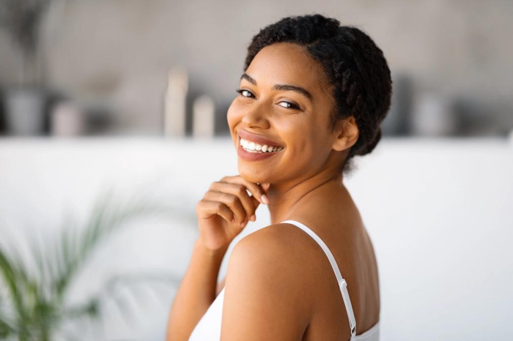 Smiling Black woman looking over her shoulder, hand to chin.
